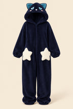A person wearing a plush dark navy cat-themed one-piece pajama with a hood, blue eyes, and white star patches on the legs, taking a mirror selfie in a bedroom.