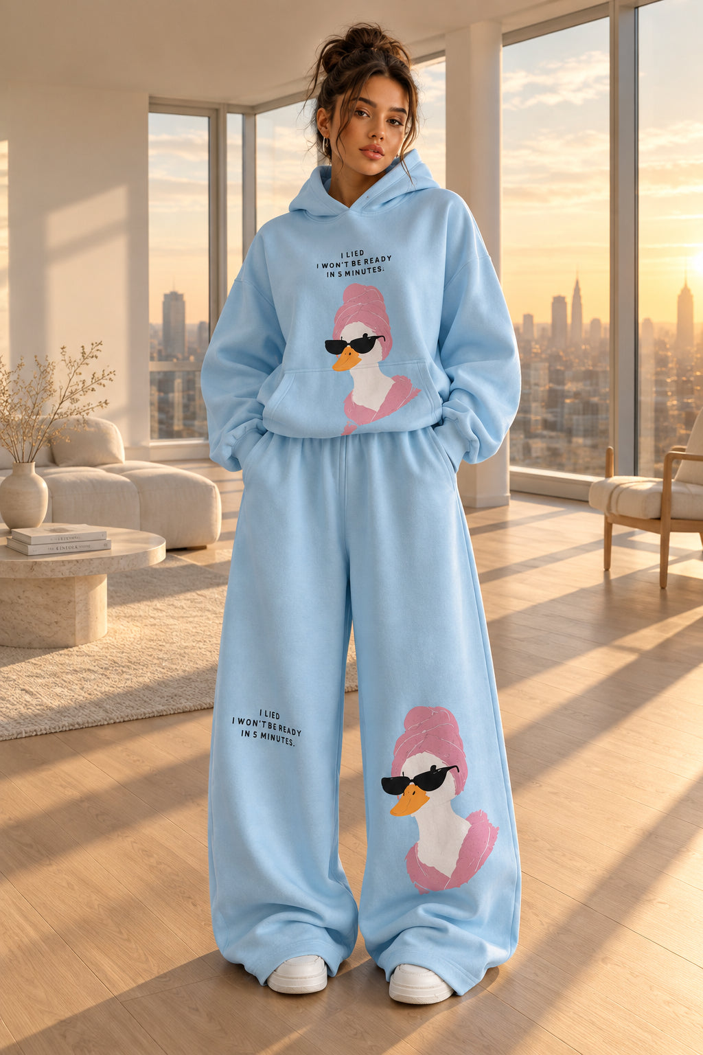 A woman modeling a light blue two-piece loungewear set with a cartoon duck graphic and text, standing in an indoor room with a dark paneled wall and gray floor. Brand text 'Rose home wear' and 'ROSE' appear as overlays.