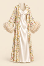 A woman models a cream satin slip dress with a matching floral print open-front cardigan featuring feathered bell sleeves, posed in an elegant indoor setting. The brand logo 'Aissaal Lingree' is visible in the top left, with a product code badge in the bottom right.