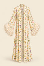 A woman models a cream satin slip dress with a matching floral print open-front cardigan featuring feathered bell sleeves, posed in an elegant indoor setting. The brand logo 'Aissaal Lingree' is visible in the top left, with a product code badge in the bottom right.