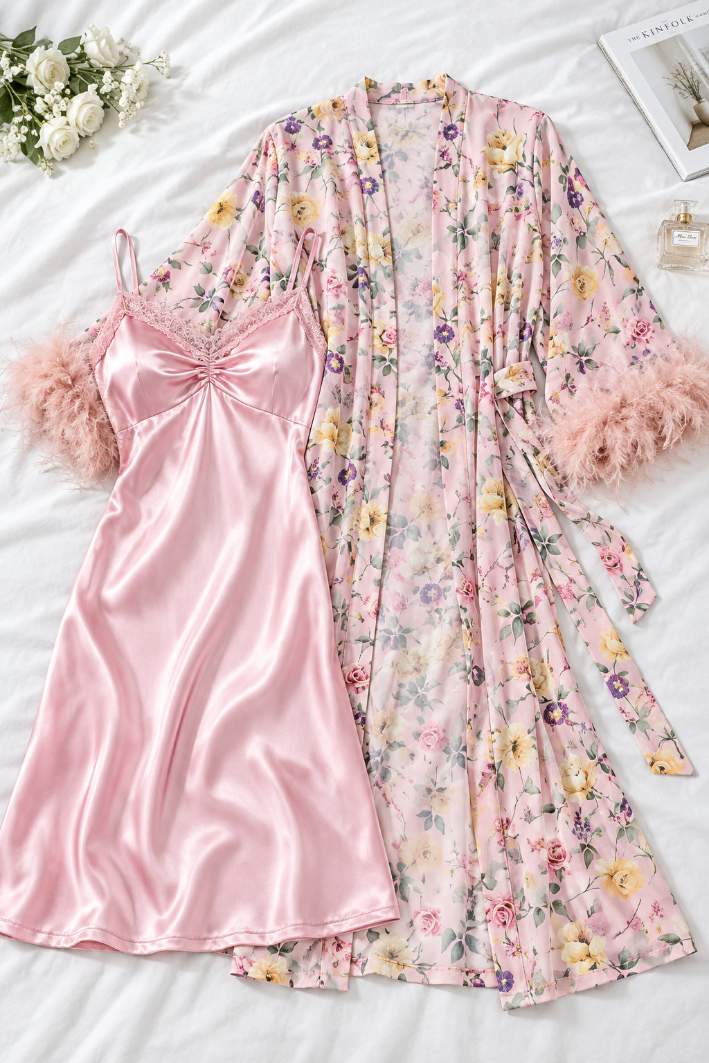A woman models a pink satin slip dress with a matching sheer floral robe featuring pink feather trim, shown in an elegant indoor setting. The brand name 'Assaial Lingree' is visible in the top left, with two smaller inset images on the left showing front and back views of the dress, and a blue code label on the right.