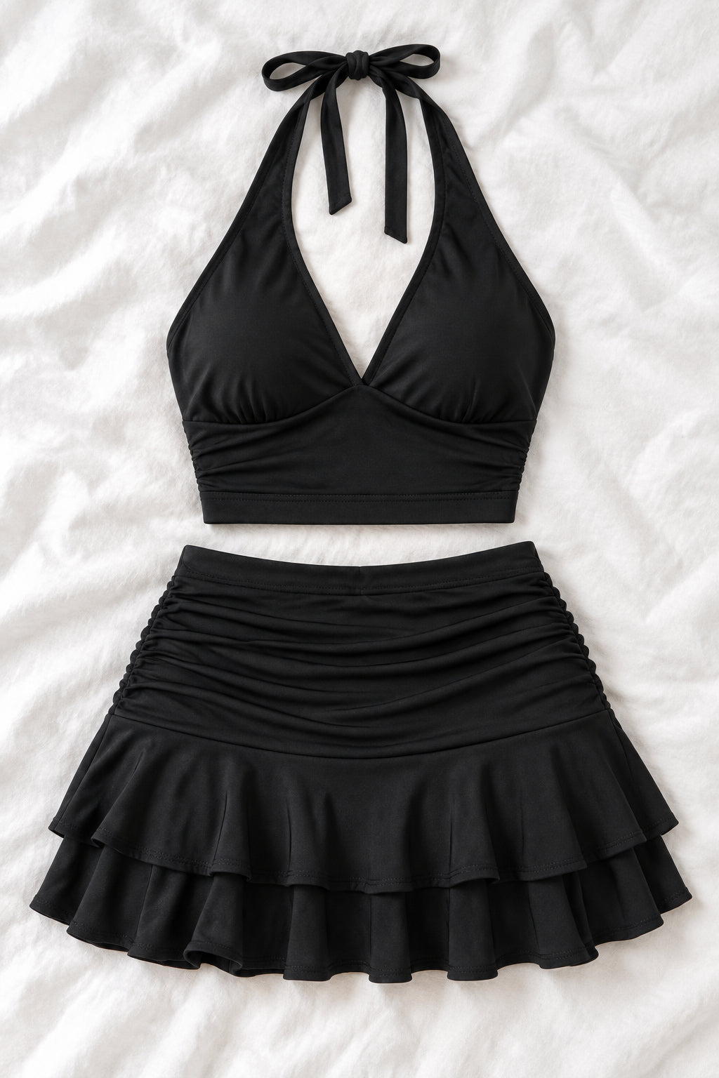 A woman modeling a black two-piece outfit consisting of a halter crop top and a ruched ruffled mini skirt, shown in front and back views side by side. The image has a pink 'Diva shop' logo at the top and contact details at the bottom.