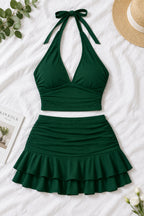 A woman modeling a dark green two-piece halter set with a wrap-style crop top and a ruched ruffled mini skirt, shown in front and back views on a split screen. The image includes a pink 'Diaa shop' logo at the top and contact details at the bottom.