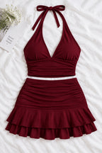 A woman modeling a two-piece burgundy halter crop top and matching ruffled mini skirt, shown in front and back views on a split-screen background. A pink 'Diaa shop' logo appears at the top, with a phone number and code text at the bottom.