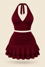 A woman modeling a two-piece burgundy halter crop top and matching ruffled mini skirt, shown in front and back views on a split-screen background. A pink 'Diaa shop' logo appears at the top, with a phone number and code text at the bottom.