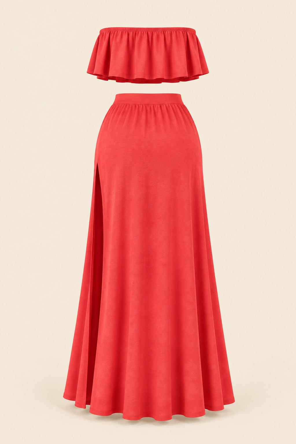 A woman models a coral-red two-piece lingerie set in a furnished indoor room. The set includes a strapless ruffled crop top and a high-slit maxi skirt.