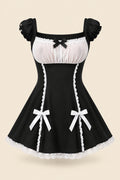A woman modeling a black and white lingerie dress with ruffled sleeves, a sheer white bust panel, a black bow at the neckline, and white lace trim with bow details at the hips. The image includes promotional text, a smaller inset showing the back view, and a pink bedroom background.