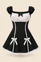 A woman modeling a black and white lingerie dress with ruffled sleeves, a sheer white bust panel, a black bow at the neckline, and white lace trim with bow details at the hips. The image includes promotional text, a smaller inset showing the back view, and a pink bedroom background.